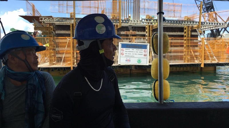 Two divers in wetsuits at pier construction site with safety signs